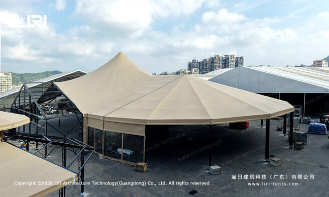 Beige high peak mixed tent showing the raised roof and polygon end from outside