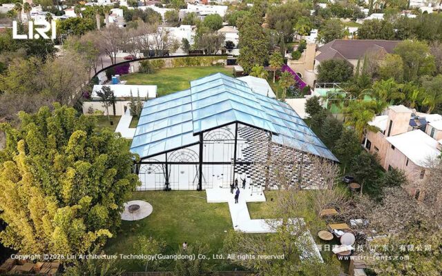 Aerial view of a transparent-roof pastoral wedding marquee in a landscaped garden